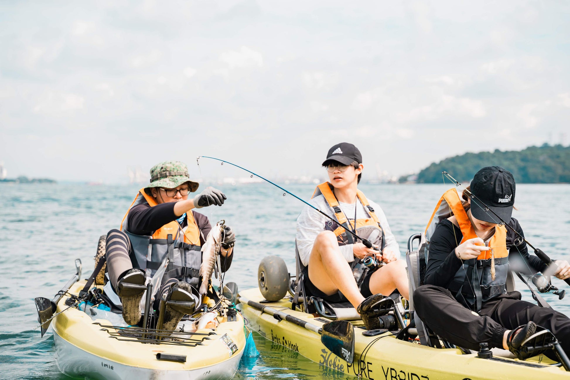 Kayak fishing guide Dom helps guest land a mangrove jack on Purehybridz Kayak Fishing Tour in Pulau Ubin