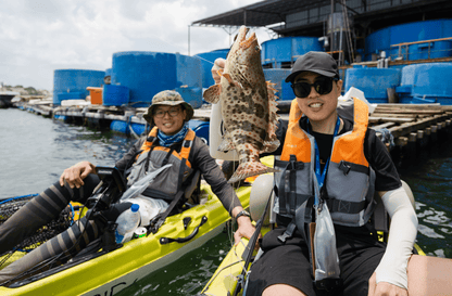 Kayak fishing guide Dom helps guest land a nice orange spotted grouper on Purehybridz Kayak Fishing Tour in Pasir Ris